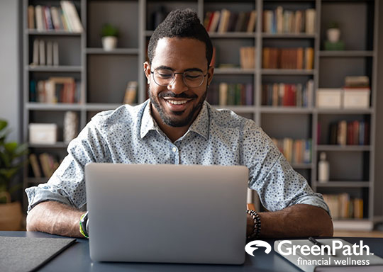 Young smiling african american businessman looking at laptop screen.