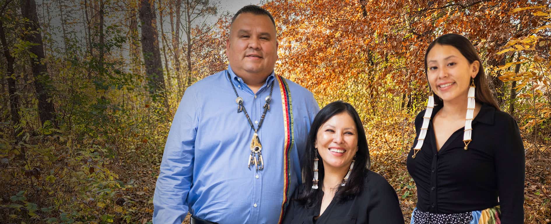 Three people standing in front of a forest background