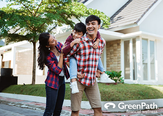 Familia de tres frente a una casa blanca