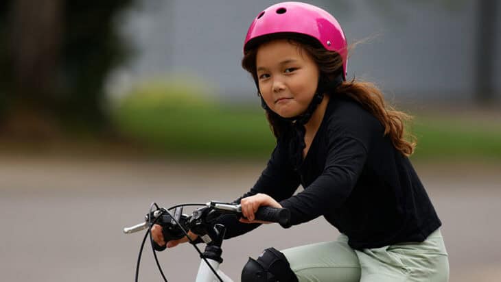 Young girl with a pink helmet riding a mountain bike in a reside